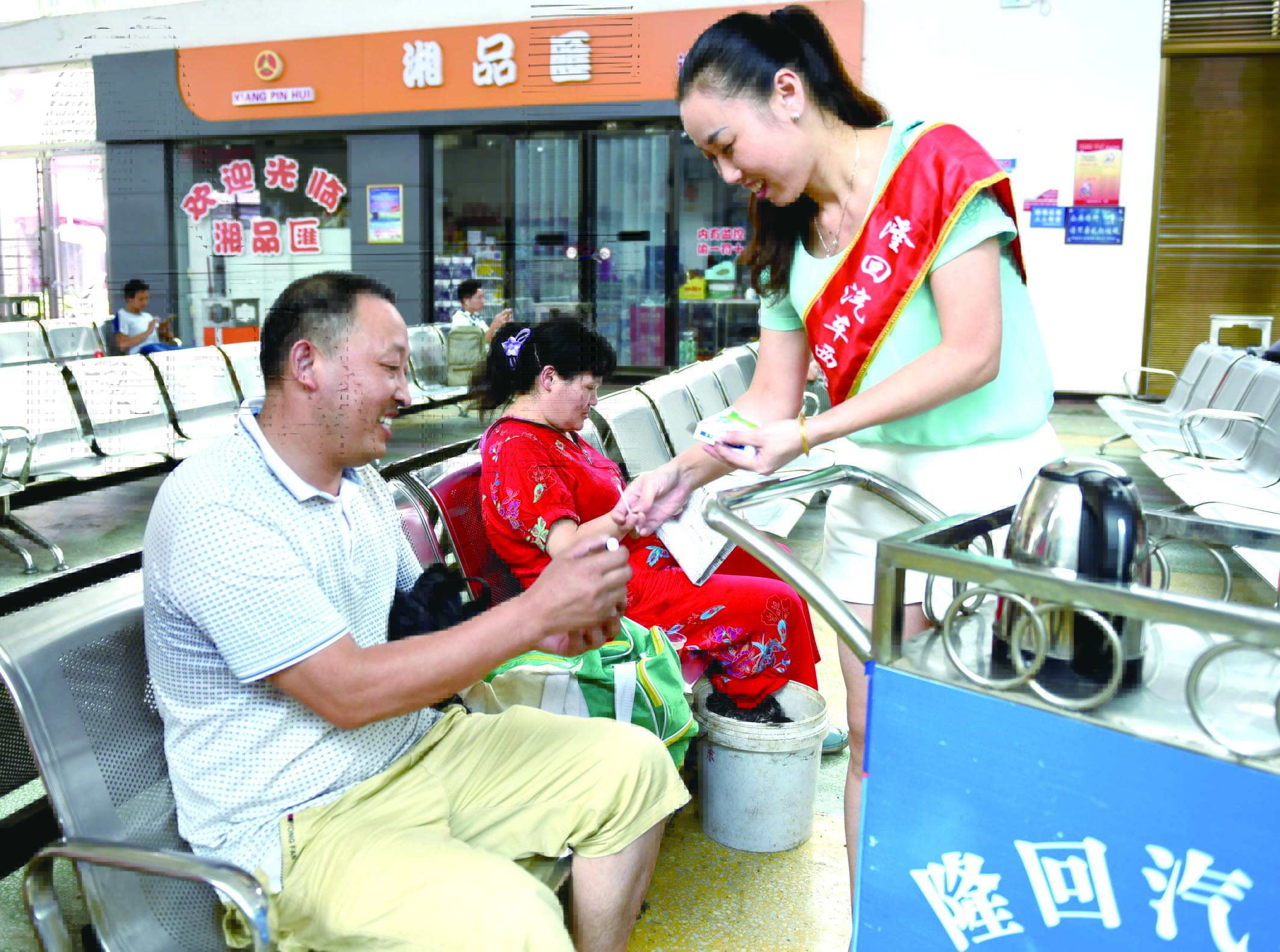 隆回分公司汽車西站工作人員正在為旅客免費(fèi)贈(zèng)送藿香正氣水。